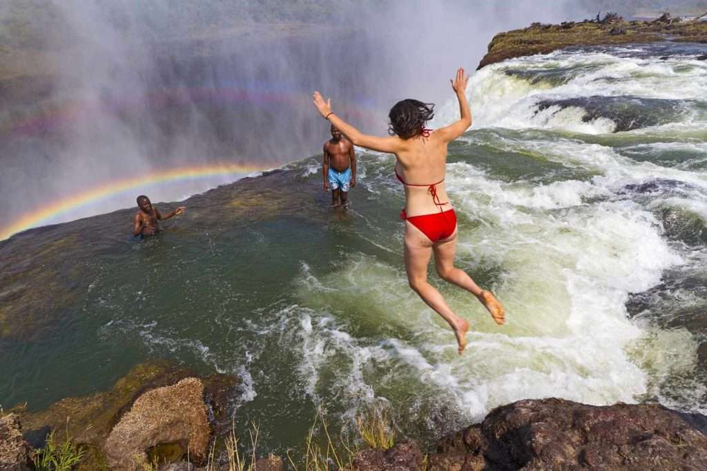 Woman having fun jumping into the Victoria Falls