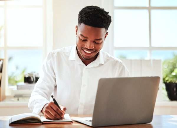 Internet, laptop and black man writing in notebook, happy freelance worker. African businessman wit Listing Standards and Requirements