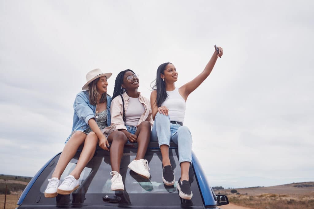 Road trip selfie of women friends on car roof with sky mockup for social media, group travel and va